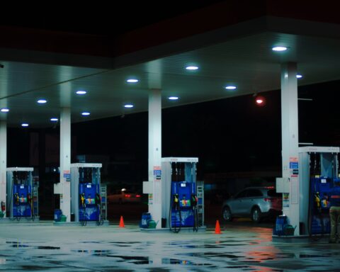 person taking a photo of blue and white gasoline station