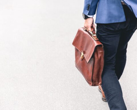 person walking holding brown leather bag
