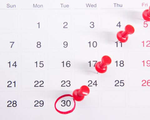 a calendar with red push buttons pinned to it