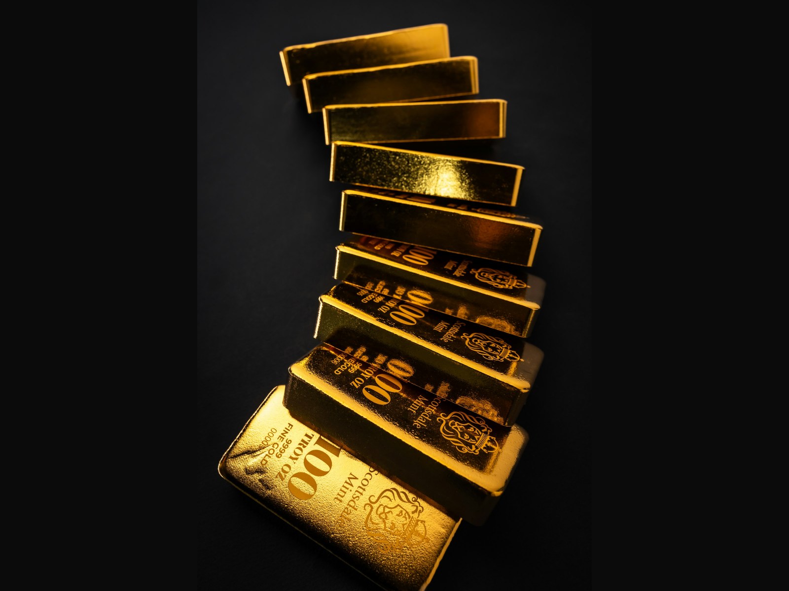 Stacked gold bullion bars on a dark background